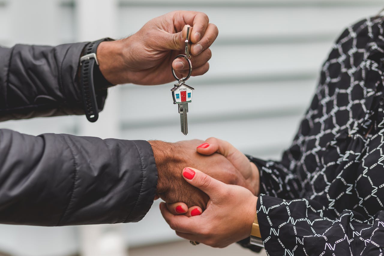 hero-homepage Close-up of a realtor handing over a house key to a new homeowner, symbolizing ownership and investment.